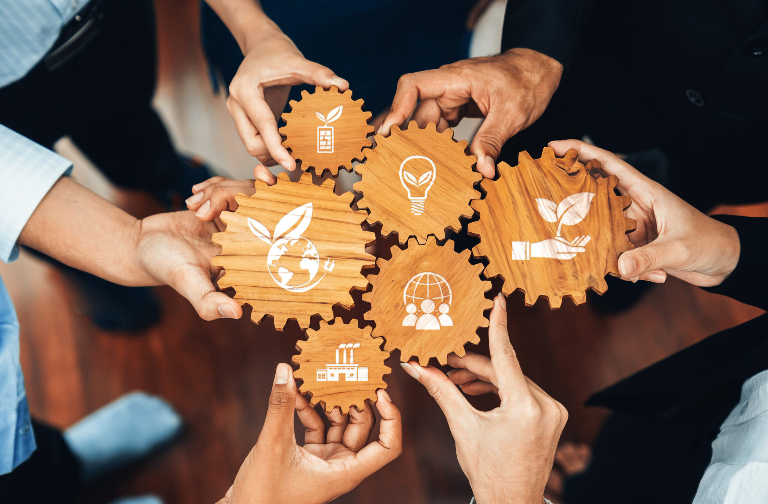 Collaborative Hands Uniting for Sustainable Business Practices Featuring Eco-Friendly Icons on Wooden Gears Representing Green Solutions and Innovations. Amity